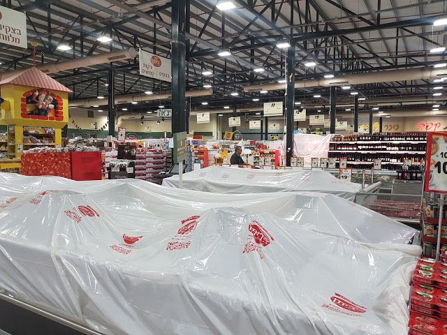 上图:从逾越节开始的7天无酵节期间,以色列的超市要有酵的食物(chametz)用白色塑料布遮盖起来。这些食物已经通过一位拉比签订合同,卖给了一位非犹太人,预付款1美元。但这些食物并没有离开超市,只是被挡住了,逾越节以后,超市还会以原价买回来。根据犹太宗教法典《哈拉卡 Halakha》,泡打粉(Baking Powder)和苏打粉(Baking Soda)不算酵,因为它们是通过化学反应、而不是生物发酵使食物膨松。